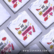 Футболка не чіпай розтану, біла, розкладена на поверхні, фон світло-сірий, принт з червоними туфлями, губами, жовтими зірочками та текстом.