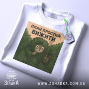 Футболка план простий вижити. Біла футболка, складена на поверхні, з принтом на грудях, фон світло-сірий, деталі принта чітко видимі, тег на рукаві.