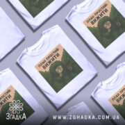 Футболка план простий вижити. Білі футболки, розкладені на поверхні, з принтом на грудях, фон світло-сірий, кілька футболок з однаковим принтом.