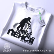 Футболка принц пенсії піски. Біла футболка, складена на поверхні, принт на видимій частині, фон світлий, деталі принта чітко видимі, з етикеткою на комірці.