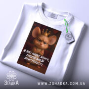 Футболка радіти моїй присутності, біла, зображена на плоскій поверхні, фон світло-сірий, принт з мишкою в короні та текстом на українській мові, з етикеткою.