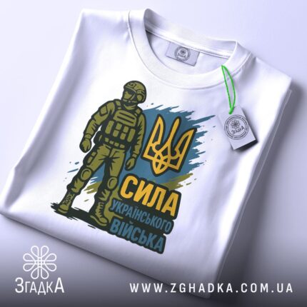 Футболка Сила українського війська, біла, розкладена на поверхні, фон світло-сірий, принт з воїном у формі та тризубом, присутня етикетка з зеленим кантом.