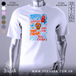 Футболка Тато супер герой, біла, зображена на манекені, фон світло-сірий, принт містить кольорові елементи: червоний супергерой, череп з окулярами, текст у різних кольорах.