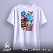 Футболка Тато супер герой, біла, підвішена на вішалці, фон світло-сірий, принт яскравий з написами та графічними елементами.