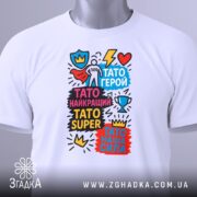 Футболка Тато супер герой, біла, зображена на манекені з близького ракурсу, фон сірий, принт яскравий з написами та графічними елементами.