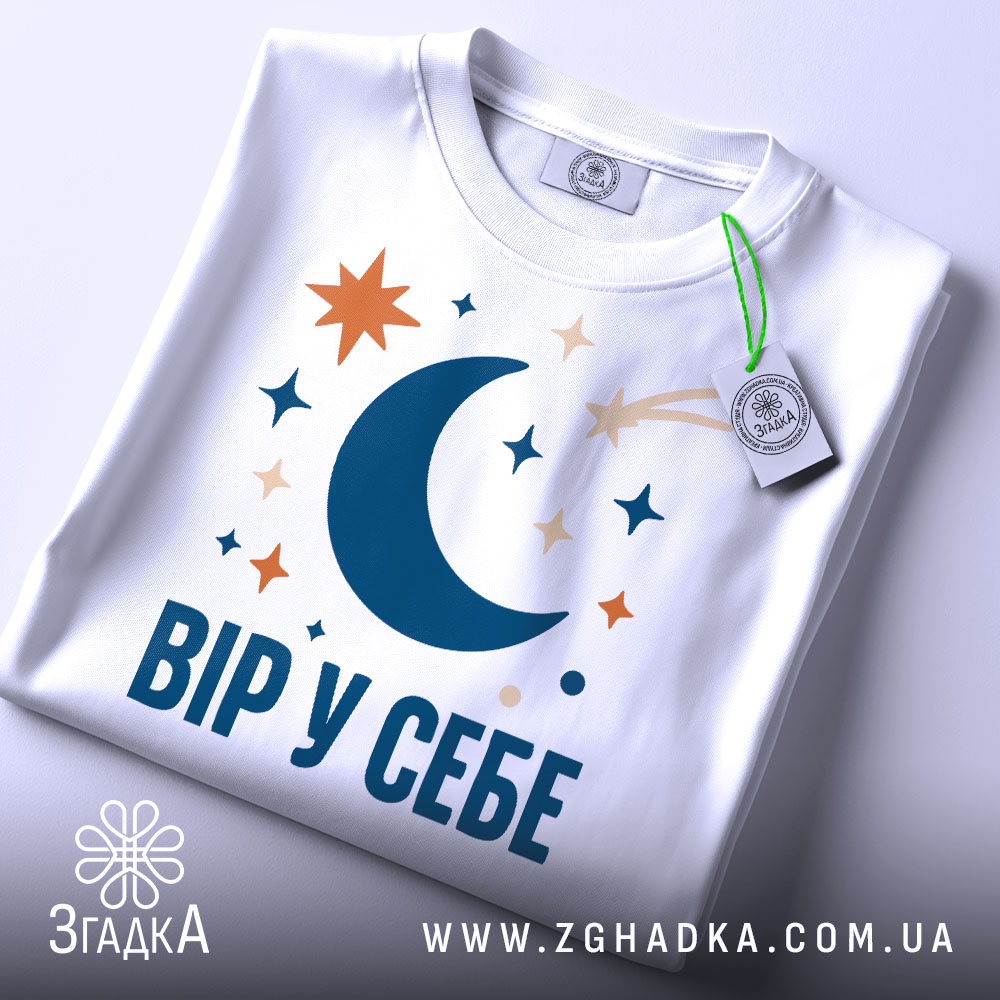 Футболка Вір у себе, біла, крупний план, принт з місяцем, зірками та кометою, фон світлий.