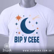 Футболка Вір у себе, біла, на манекені, крупний план, принт з місяцем, зірками та кометою, фон сірий.