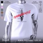 Футболка з автомобільним дизайном, біла, зображена на манекені, фон світлий, принт з малюнком свічки запалювання та текстом "Гаражний культ" червоного кольору.