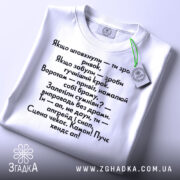 Футболка з кумедними написами, білого кольору, зображена зверху, фон світло-сірий, принт чорного кольору з текстом на українській мові, на комірці є етикетка.