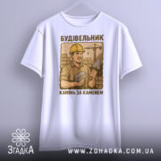 Футболка з малюнком будівельника, білого кольору, зображена з фронтального ракурсу, фон нейтральний, принт з будівельником у жовтому касці, що тримає камінь і лопату, текст під малюнком: 'Камінь за каменем'.