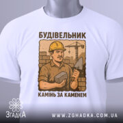 Футболка з малюнком будівельника, білого кольору, зображена з фронтального ракурсу на манекені, фон нейтральний, принт з будівельником у жовтому касці, що тримає камінь і лопату, текст під малюнком: 'Камінь за каменем'.