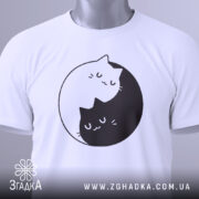 Футболка з малюнком котів білого кольору, зображена на манекені, з принтом двох котів, один з яких чорний, а інший білий, що обіймаються в кругу. Фон світло-сірий, що підкреслює яскравість принта.