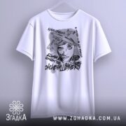 Футболка з написом свободи, білого кольору, підвішена на вішалці, фон світло-сірий, принт зображує жінку з літаками та текстами, вид спереду.