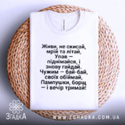 Футболка з поетичним текстом, білого кольору, складена на плетеній основі, фон світлий, текст чорного кольору, розташований по центру, з чіткими рядками.