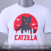 Футболка з принтом Catzilla білого кольору, зображена з фронтального ракурсу на манекені, фон світло-сірий, принт містить чорного кота на червоному фоні з силуетами міста та вертольотами.