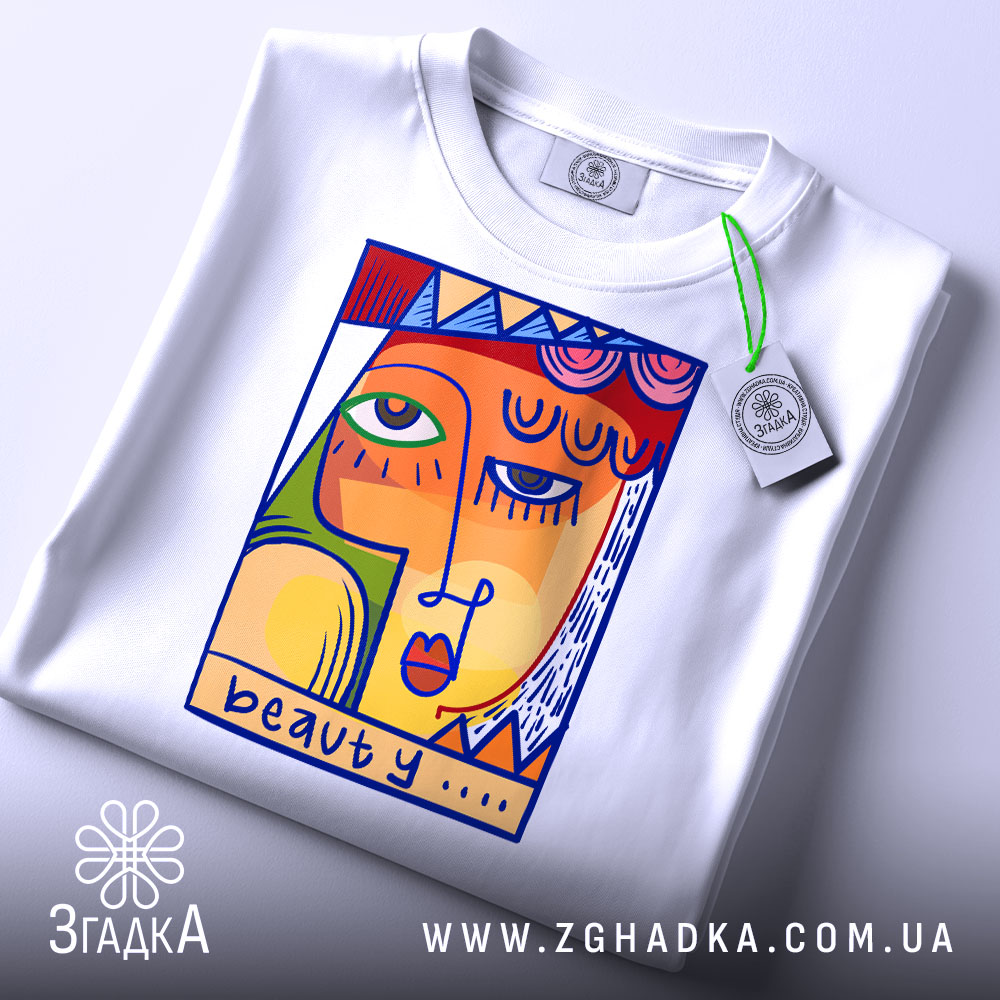 Футболка з текстом beauty, білого кольору, зображена зверху, фон світло-сірий, принт з абстрактним обличчям в яскравих кольорах, з етикеткою на комірці.