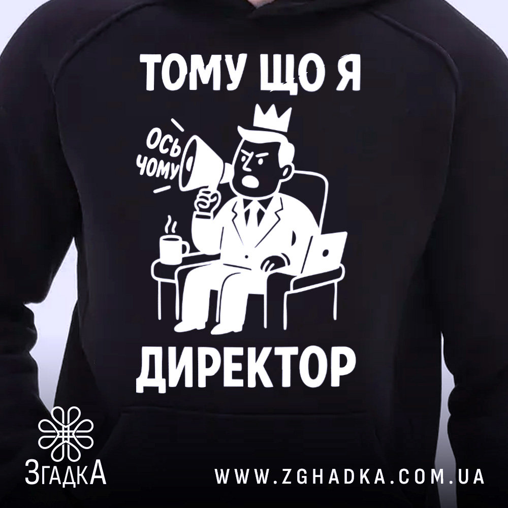 Худі я директор подарунок. Чорний колір, ракурс з близької відстані, фон світлий. Принт з малюнком директора, який тримає мегафон, текст "ТОМУ ЩО Я ДИРЕКТОР". Капюшон видимий, манжети з еластичної тканини.