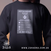 Світшот автономний робот подарунок чорного кольору, зображений на людині з довгим волоссям, ракурс спереду, фон з нейтральним освітленням, принт з інформацією про автономного робота, кругла горловина, манжети з трикотажної резинки, трикотажна резинка на поясі, фактура м'яка та комфортна.