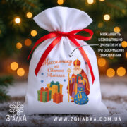 Мішечок до Дня Миколая на фоні ялинки та вогників, білий габардин 20×30 см з червоною стрічкою і принтом Миколая з подарунками.