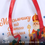 Мішечок до Дня Миколая крупним планом, деталі сублімаційного друку та тексту персоналізації на білому габардині.