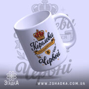 Чашка для прекрасної королеви. Чашка білого кольору з принтом, з ракурсу спереду. Фон світло-фіолетовий з елементами корони. Ручка класичної форми, край гладкий, поверхня глянцева.