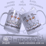 Чашка гуси роздовбаї, дві білі чашки з кольоровим принтом, що показують трьох гусей, розташовані під кутом, фон світло-фіолетовий, ручки класичні, краї рівні, глянцева поверхня.