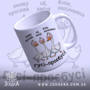 Чашка гуси роздовбаї, біла з кольоровим принтом, показує трьох гусей з комічними виразами обличчя, ручка класична, фон світло-фіолетовий, край рівний, глянцева поверхня.