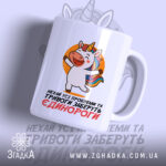 Чашка єдинороги заберуть: біла чашка з яскравим принтом єдинорога на оранжевому фоні, ручка з класичним дизайном, глянцевий край, текст на українській мові, що говорить про проблеми та тривоги.