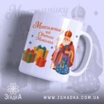 Чашка іменна до Дня Миколая, біла, з ракурсом спереду, фон світло-фіолетовий, принт з малюнком Святого Миколая та подарунків, ручка стандартна, край рівний, глянцева поверхня.