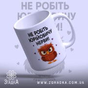 Чашка мем для офісу, біла, зображена з верхнього ракурсу, на фоні світло-фіолетового кольору, принт з малюнком сови та текстом "НЕ РОБІТЬ ЮРІЙОВИЧУ НЕРВИ!", ручка класична, край рівний, глянцева поверхня.
