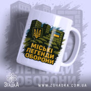 Чашка міські легенди оборони, біла, зображена з правого ракурсу, на фоні стилізованих будівель, принт з гербом України та написом на чорному фоні, ручка класична, край рівний, глянцевий.
