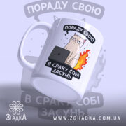 Чашка нахабний кіт, біла з кольоровим принтом, зображення нахабного кота з комп'ютером на чорному фоні, ручка з правого боку, край рівний, матова поверхня.