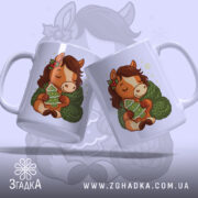 Чашка новорічний коник подарунок, біла, зображення коника з зеленим светром, тримає ялинку, ручки з обох боків, край рівний, глянцева поверхня, фон світло-синій.