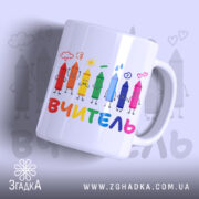 Чашка початкова школа вчитель, біла з кольоровими олівцями на принті, напис 'ВЧИТЕЛЬ' внизу, ручка кругла, край рівний, глянцева поверхня, фон світло-сірий.