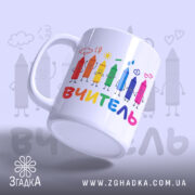 Чашка початкова школа вчитель, біла з кольоровими олівцями на принті, напис 'ВЧИТЕЛЬ' внизу, ручка кругла, край рівний, глянцева поверхня, фон світло-сірий.