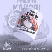 Чашка пустотливий єнот. Чашка білого кольору з малюнком єнота, що лежить на фоні вогню, з боку. Ручка кругла, край рівний, поверхня глянцева. Напис: 'Грішити та кайфувати! Бешкетуй та насолоджуйся!'