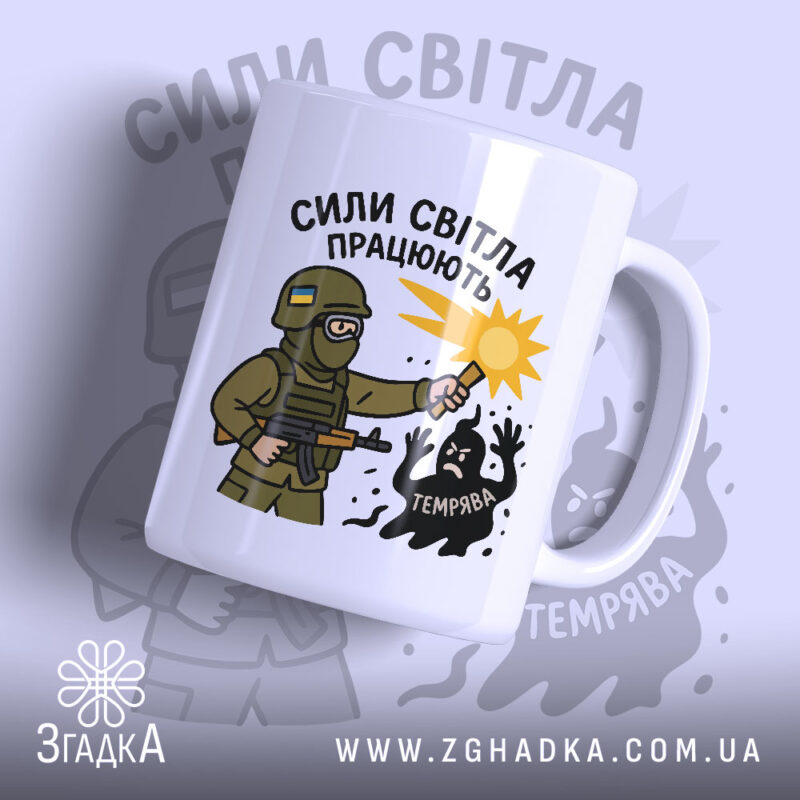 Чашка сили світла працюють, біла з малюнком, показує військового з ліхтарем, на фоні світло-сірого кольору, з написом 'СИЛИ СВІТЛА ПРАЦЮЮТЬ', ручка стандартна, край рівний, матова поверхня.