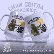 Чашка сили світла працюють, біла з малюнком, зображає дві чашки, одна з військовим з ліхтарем, на фоні світло-сірого кольору, з написом 'СИЛИ СВІТЛА ПРАЦЮЮТЬ', ручки стандартні, краї рівні, матова поверхня.