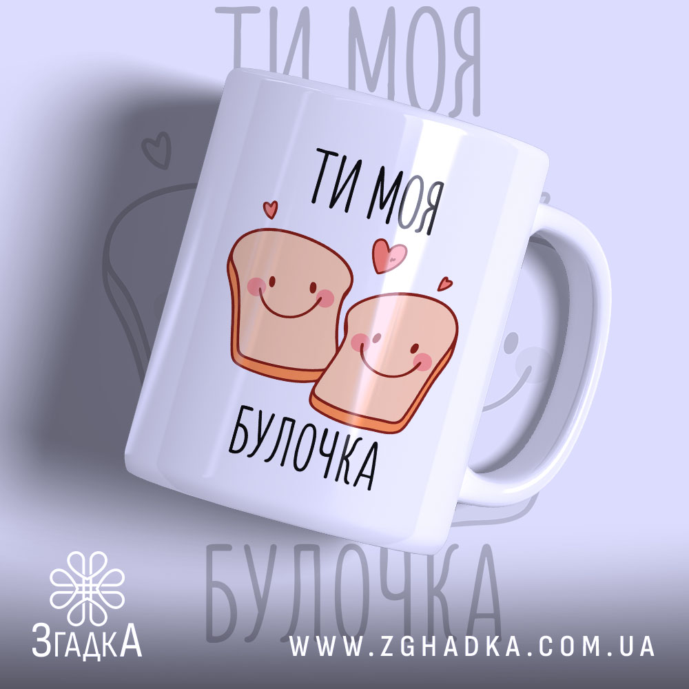 Chashka Ty Moia Bulochka Dlia Shchodennoho Natkhnennia 1 Чашка ти моя булочка, біла з малюнком двох усміхнених шматочків хліба, написом 'ТИ МОЯ БУЛОЧКА', фон світло-фіолетовий, ручка округла, край рівний, глянцева поверхня.