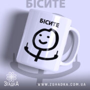 Чашка з мемом Бісите, біла, з легким глянцем, зображення на передній частині, де напис 'БІСИТЕ' чорного кольору, з усміхненим персонажем, що показує два пальці, ручка класична, край рівний.