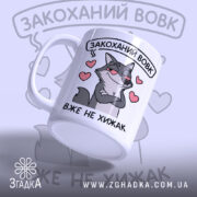 Чашка закоханий хижак, біла з малюнком сірого вовка, що має хитру усмішку, на фоні сердечок, ручка класична, край рівний, глянцевий.