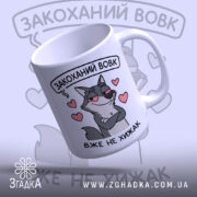 Чашка закоханий хижак, біла з малюнком сірого вовка, що має хитру усмішку, на фоні сердечок, ручка класична, край рівний, глянцевий.
