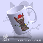 Чашка злий новорічний кіт, біла, зображення кота в червоній шапці та гірлянді, ручка з правого боку, глянець на поверхні, фон світло-сірий.