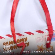 Дитячий подарунковий мішечок крупним планом — фрагмент з написом і червоною стрічкою.