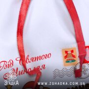 Персоналізований дитячий подарунковий мішечок крупним планом — напис “Від Святого Миколая” і святкові марки.