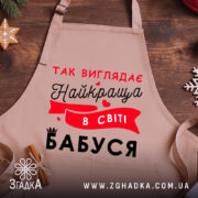 Фартух найкраща в світі бабуся на фоні святкового столу з пряниками, детальний вигляд принта крупним планом.