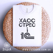 Футболка 1с хаос стрес, складена футболка на плетеній тарілці, ракурс зверху, фон світлий, принт чорний з текстом 'ХАОС СТРЕС i 1С'.