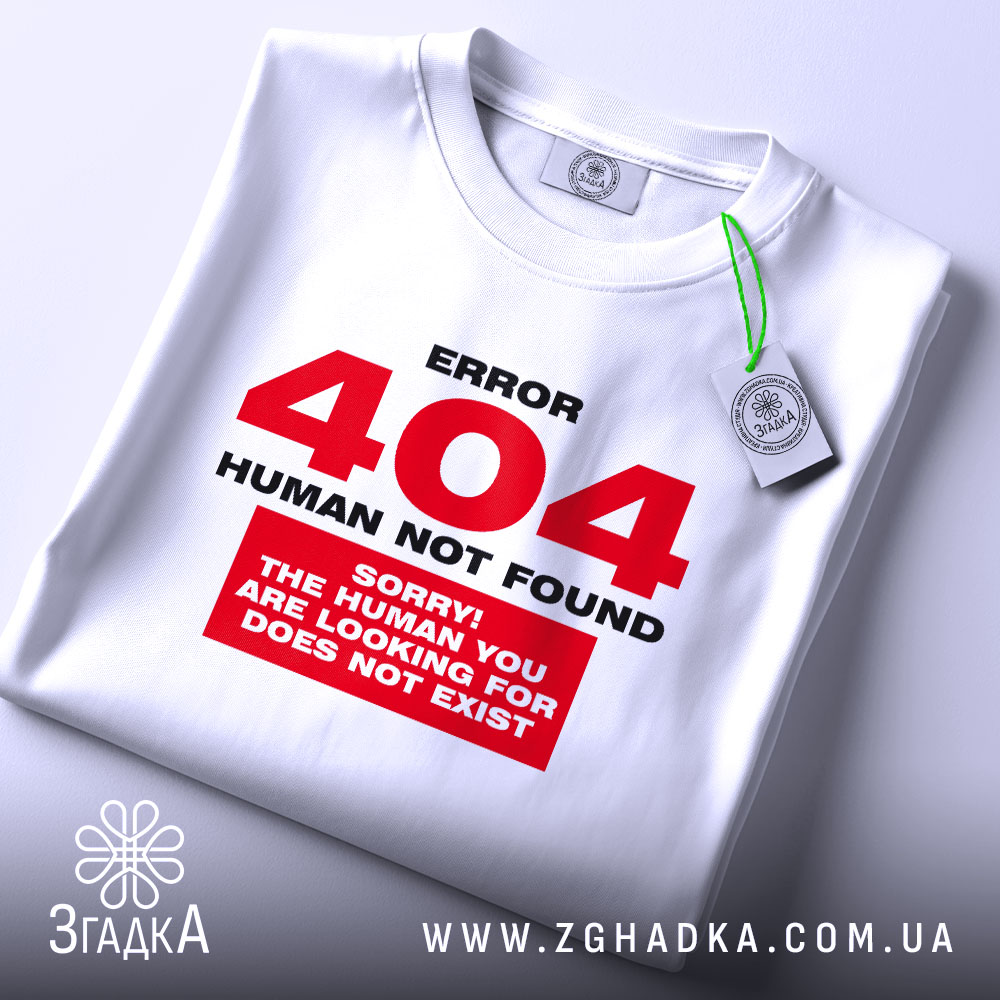 Футболка 404 human not found, біла, складена на поверхні, фон світло-сірий, принт червоний з текстом 'ERROR 404 HUMAN NOT FOUND' та 'SORRY! THE HUMAN YOU ARE LOOKING FOR DOES NOT EXIST', на комірці зелена етикетка.