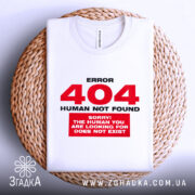 Футболка 404 human not found, біла, складена на плетеній основі, фон світло-сірий, принт червоний з текстом 'ERROR 404 HUMAN NOT FOUND' та 'SORRY! THE HUMAN YOU ARE LOOKING FOR DOES NOT EXIST'.