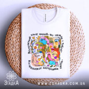 Футболка абстрактні емоції, біла, зображена зверху на плетеному кошику, фон білий, принт кольоровий, з абстрактними обличчями та текстом, видима етикетка на горловині.